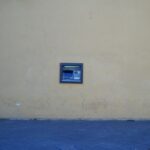 Bancomat rotto con un cartello "Fuori uso" e una persona preoccupata che cerca alternative per prelevare denaro.